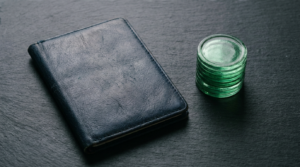 kucoin review - closed ID wallet beside a stack of green glass coins on slate